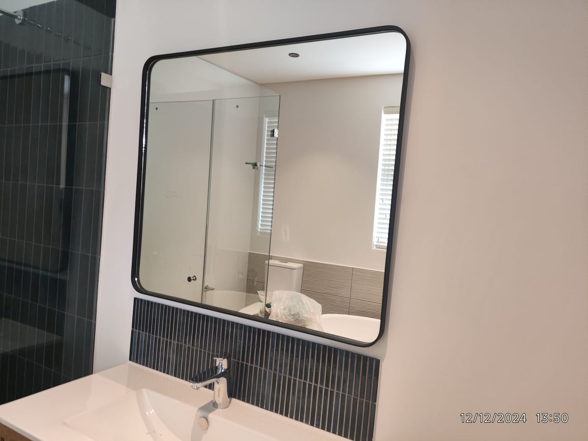 Black-framed bathroom mirror installed securely above a basin